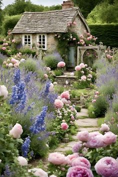 a garden filled with lots of flowers next to a small house on top of a hill