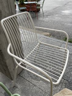 a white metal chair sitting on top of a sidewalk