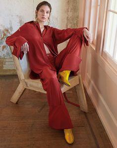 a woman sitting in a chair with her legs crossed wearing red pants and yellow heels