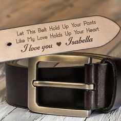 a leather belt with an engraved message on the bottom, and a metal buckle that says let this belt hold up your pants like my love holds up your heart i love you