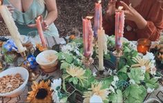 two people sitting at a table with candles in front of them and flowers on the table