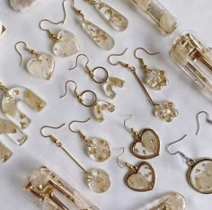 many different types of earrings are laying on a white tablecloth and there is no image here to provide a caption for