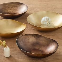 three gold bowls sitting on top of a wooden table