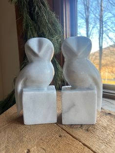 two white marble sculptures sitting on top of a wooden table next to a christmas tree