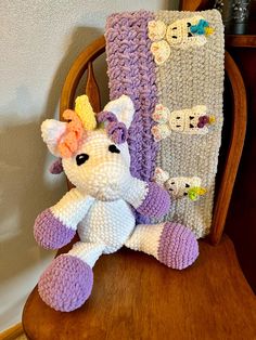 a stuffed animal sitting on top of a wooden chair next to a crocheted blanket