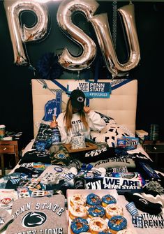 a woman sitting on top of a bed surrounded by balloons and t - shirt designs