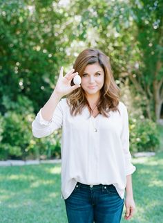 a woman in jeans and a white shirt is holding an object up to her face