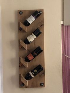 a wooden wine rack holding several bottles of wine on it's sides and hanging from the wall