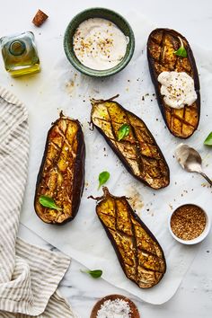 grilled eggplant on parchment paper with spoons and small bowl of yogurt