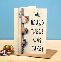 a card with two dogs peeking out from behind a door and the words, we heard there was cake