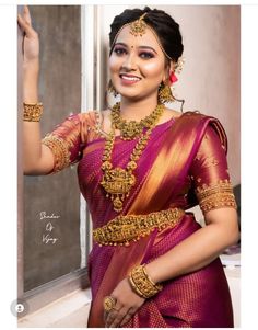 a woman in a red and gold sari posing for the camera with her hand on her hip