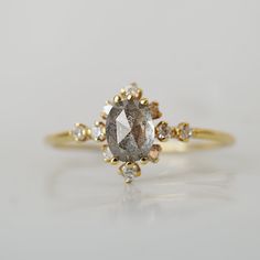 a fancy ring with an oval cut diamond surrounded by small white and brown diamonds on the side