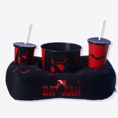 three red cups sitting on top of an inflatable batman pillow with straws