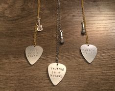 three guitar pick necklaces with writing on them