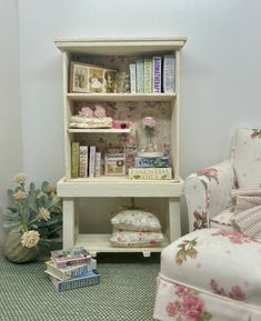 a room with a chair, book shelf and flowers on the floor next to it