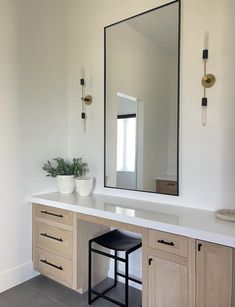 a bathroom vanity with two stools and a large mirror on the wall above it