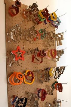 there are many pairs of scissors hanging on the pegs in this wall mounted display