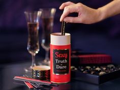 a person is holding a stick in front of a bottle of truth dare on a table