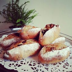 several pastries are on a plate with white doily and green plant in the background