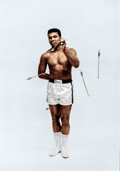 a man with no shirt and white shorts is standing in the air holding two arrows