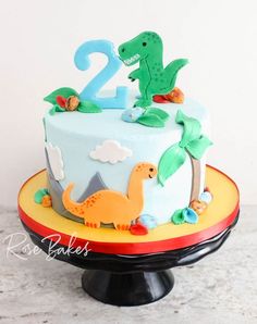 a dinosaur themed birthday cake with the number two on top