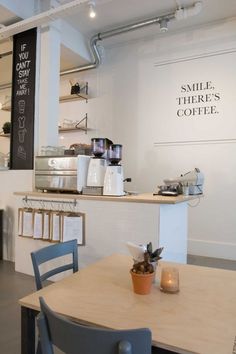 there is a small table and chairs in this coffee shop with signs on the wall