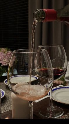 wine being poured into two glasses on a table