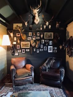 a living room with deer heads mounted on the wall and leather chairs in front of it