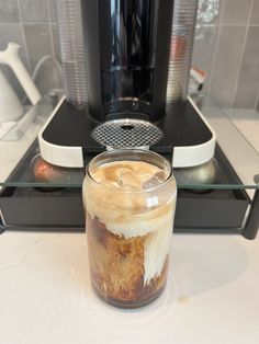 a jar filled with ice cream sitting on top of a counter next to a coffee maker