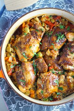 chicken and vegetable stew in a bowl on a blue tablecloth next to a wooden spoon