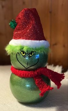 a green and red christmas ornament with a santa hat on it's head