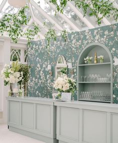 the bar is decorated with white flowers and greenery in front of a green wall