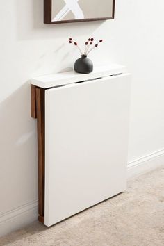 a white cabinet with a black vase on top