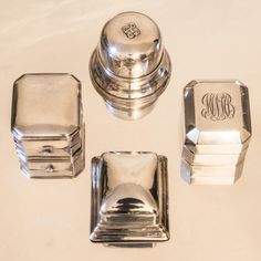 four silver objects on a white surface with the monogrammed initials and letters engraved on them