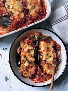 a white plate topped with lasagna next to a casserole dish