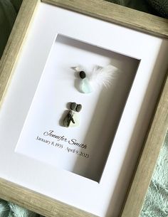 a white frame holds a couple's wedding date and two small rocks in the shape of a bird