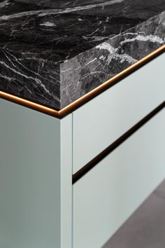 a black and white marble counter top with gold trimmings on the bottom edge