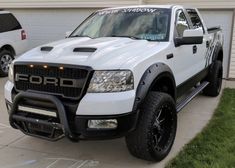 a white pick up truck parked in front of a garage