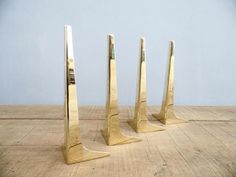 three metal sculptures sitting on top of a wooden floor next to each other in front of a blue wall