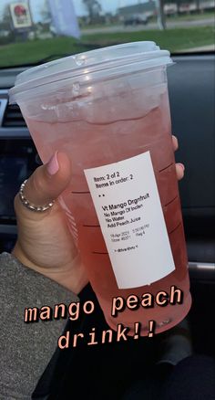 a person holding up a plastic cup filled with liquid in the back seat of a car