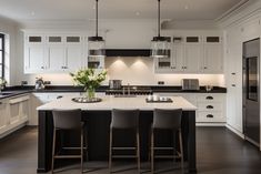 a large kitchen with white cabinets and black counter tops, along with bar stools