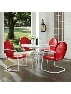 a white table and red chairs on a porch