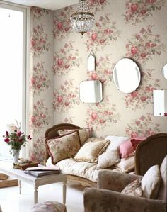 a living room with floral wallpaper and mirrors on the wall above it's couch