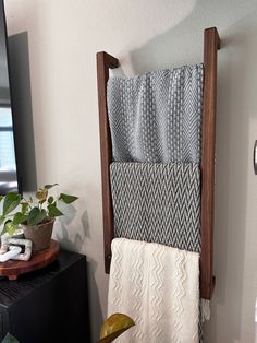 a towel rack with two towels hanging on it's sides and a potted plant next to it