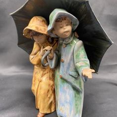 two ceramic figurines are holding an umbrella