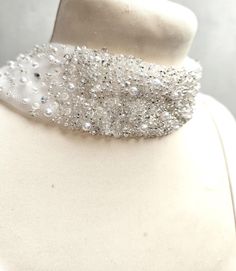 a white mannequin with silver beading on it's neck and collar