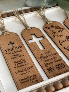 three wooden tags with names on them in a white box next to some chocolates