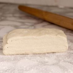 a piece of bread sitting on top of a counter next to a wooden spatula