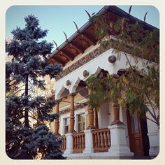 a white building with wooden balconies on the front porch and balcony railings