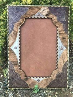 an old photo frame with rope and wood in the center on some green grass,